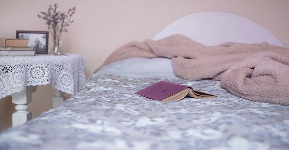 nightstand bed blankets ruffled book open flowers